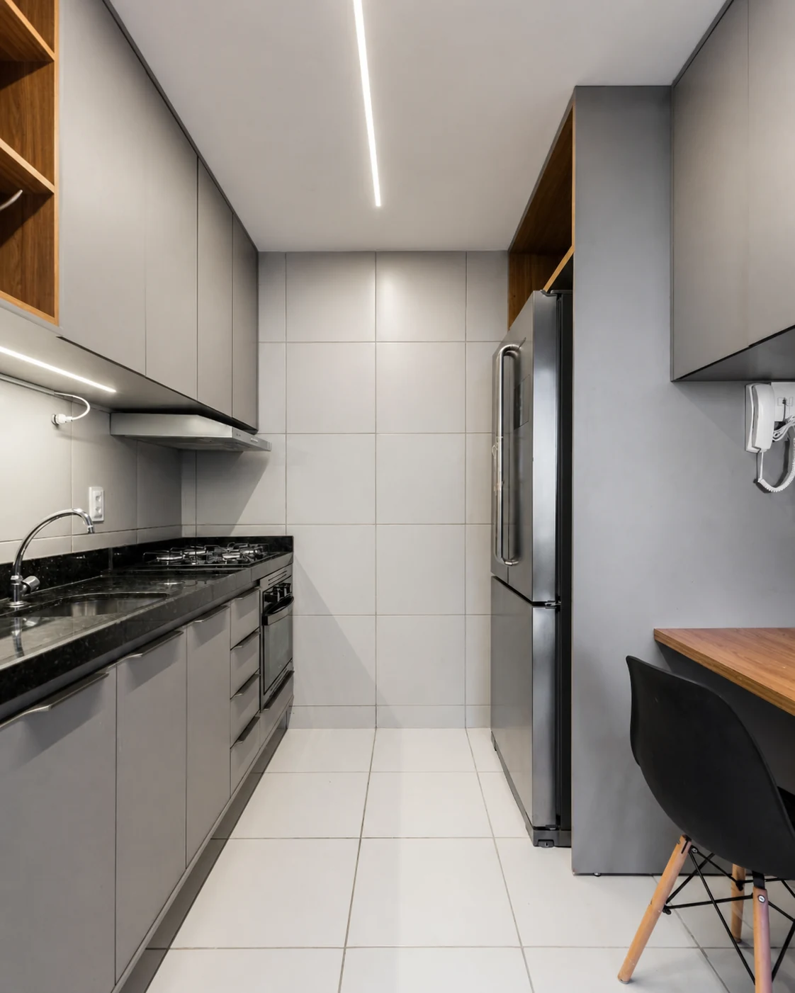 Cozinha compacta cinza com armários sob medida e bancada em granito preto